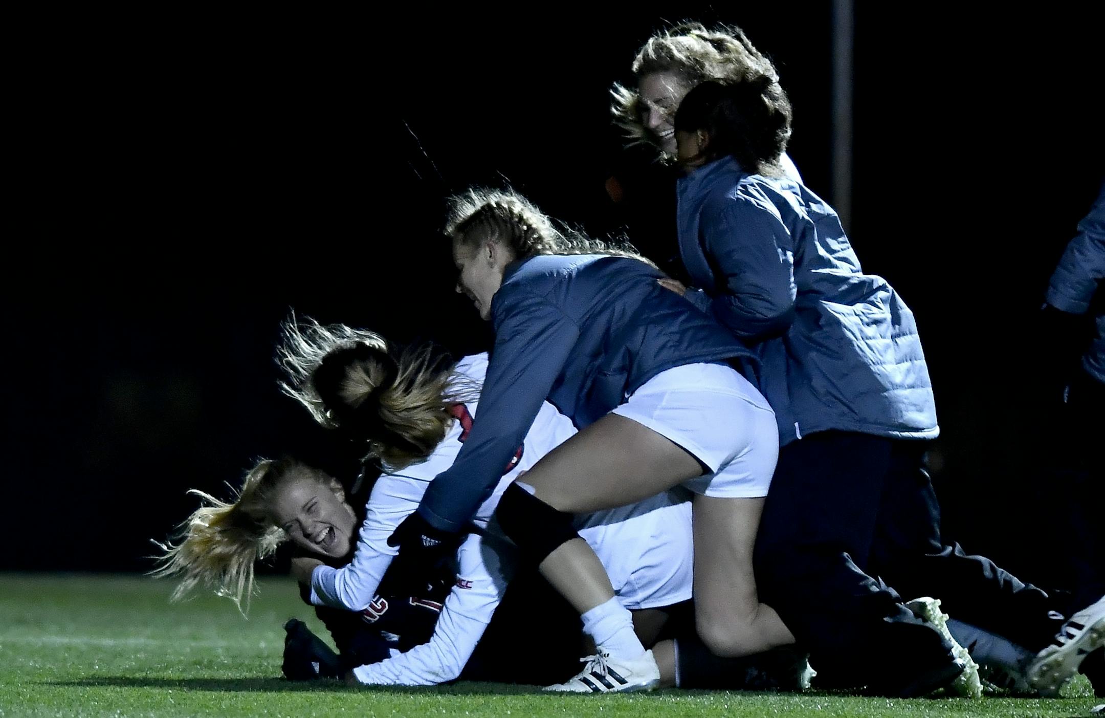 NC State players piled onto goalkeeper Sydney Wootten (12) after the team beat Minnesota 4-2 in PKs Saturday night.