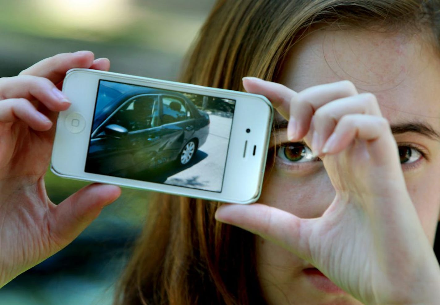 Hannah Waldfogel held up a picture of her car that was damaged when someone ran into it and drove away in Minneapolis. Police, who have a vehicle license number, have shelved the case.