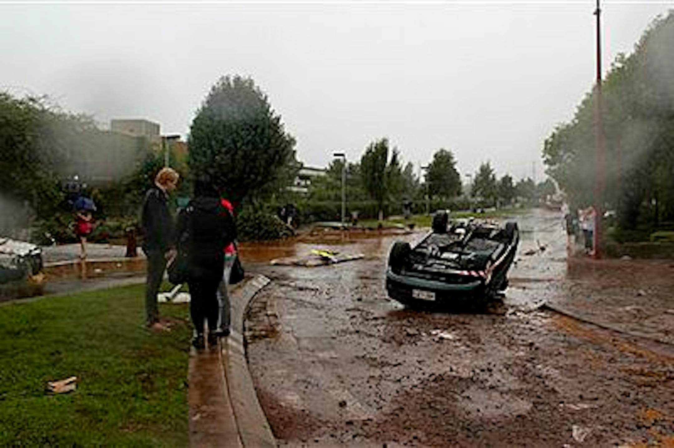 People survey the damage after a flash flood tossed vehicles down a street in Toowoomba, Australia, Monday, Jan. 10, 2011. Flash floods swept through the northeastern Australian community killing one woman, trapping others in cars and leaving some clinging to trees as relentless rains brought more misery to a region battling its worst flooding in decades. (AP Photo/ABC) AUSTRALIA OUT