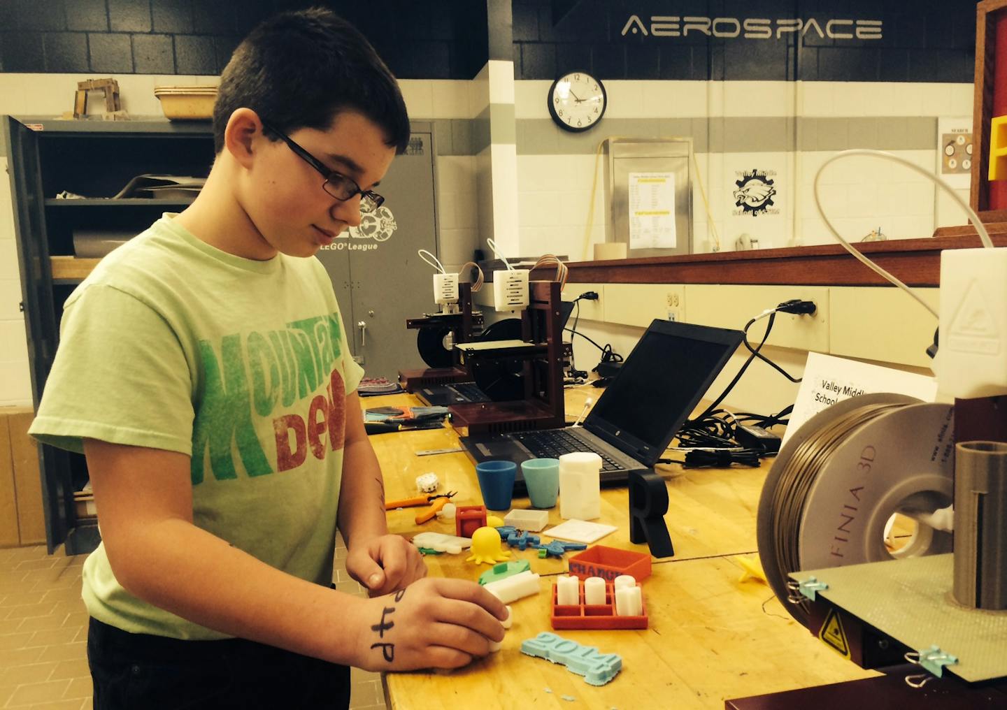 Valley Middle School student Devin Martin, grade six, waits for his vinyl decal to be ready and looks at items made with the 3-D printer.