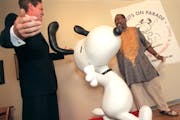 Then-Mayor of St. Paul Norm Coleman and Lowertown artist Ta-coumba T. Aiken unveiled a statue of Snoopy at the Black Dog Cafe in 2000.