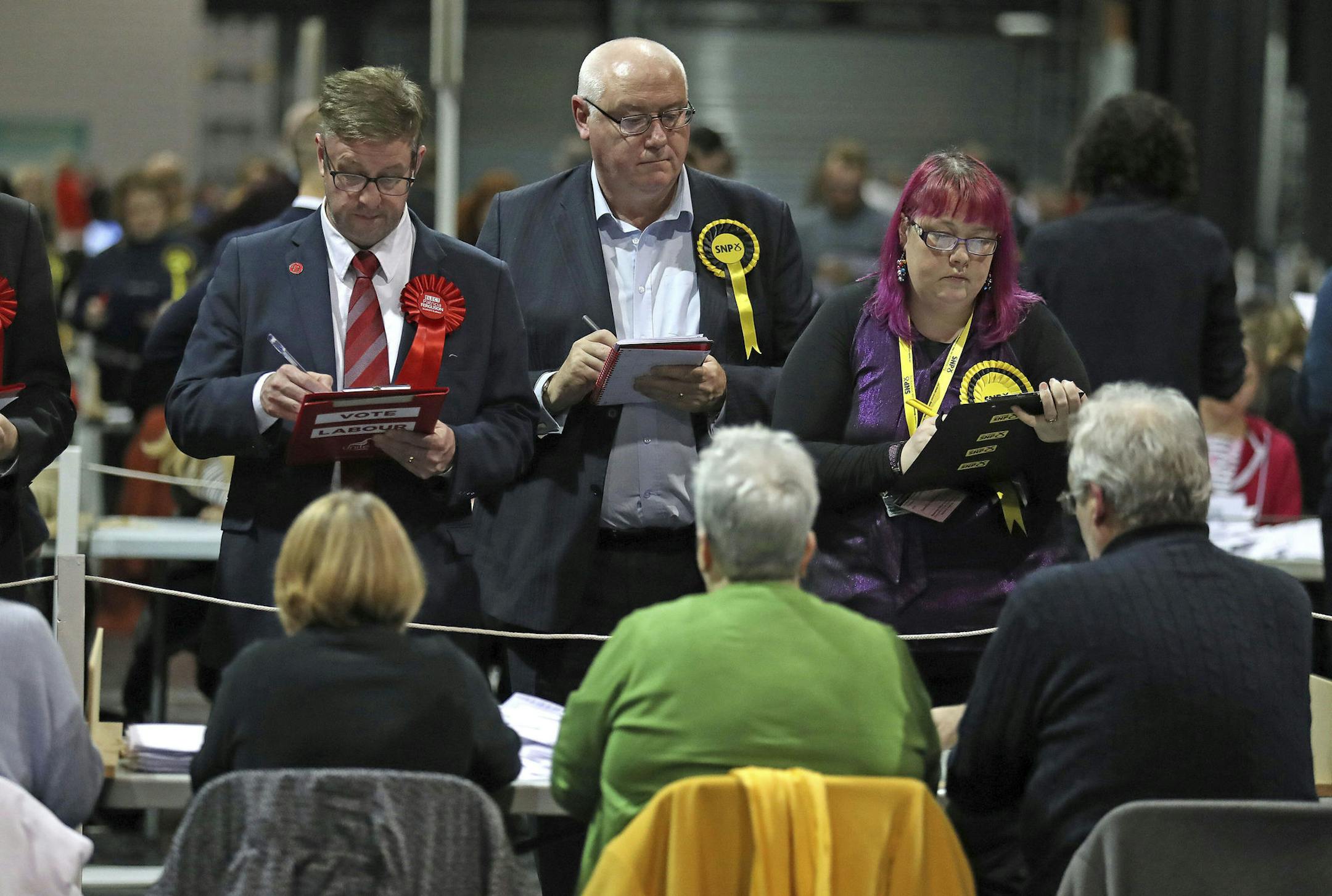 Election agents watch tellers as ballot papers are counted at the SEC Centre in Glasgow, Scotland Thursday Dec. 12, 2019. An exit poll in Britain’s election projects that Prime Minister Boris Johnson’s Conservative Party likely will win a majority of seats in Parliament. That outcome would allow Johnson to fulfil his plan to take the U.K. out of the European Union next month. (Andrew Milligan/PA via AP)