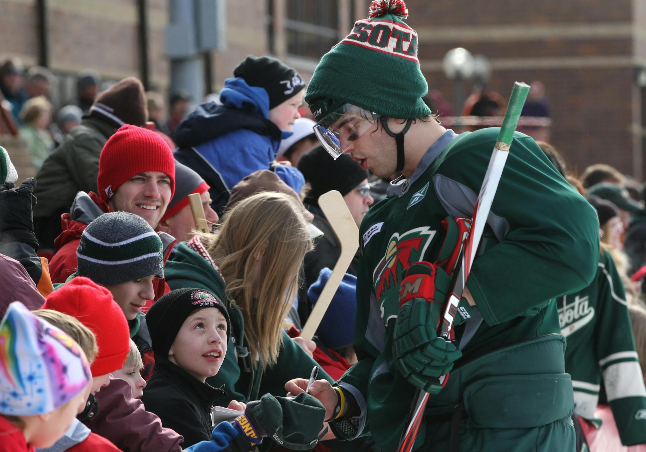 (center) Minnesota Wild defenseman Brent Burns signed autographs for the hundreds of hockey fans that turned out to see the Wild hold their first ever, outdoor practice at the John Rose Oval.