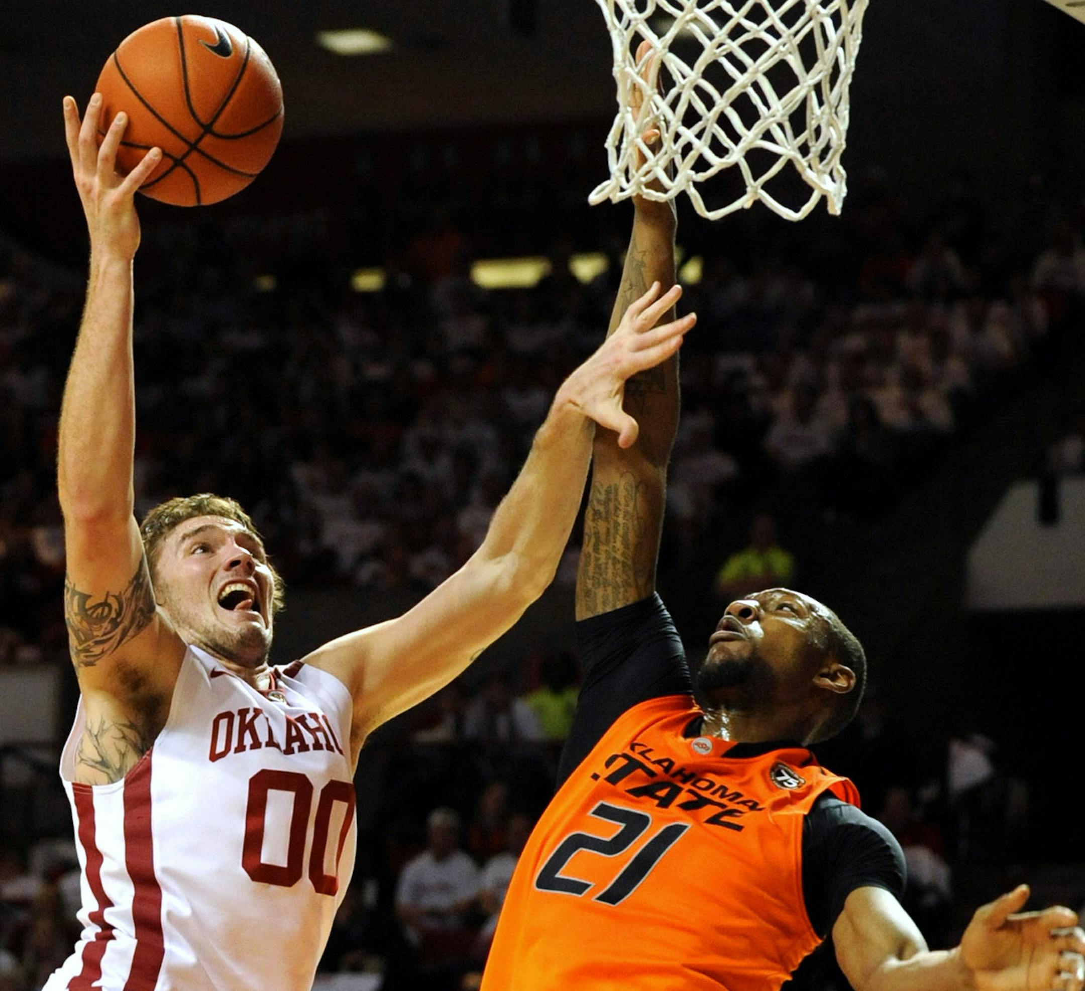 Oklahoma State guard Marcus Smart (33) watches as Oklahoma forward Ryan Spangler (00) takes a shot over Oklahoma State forward Kamari Murphy (21), center during the second half of an NCAA college basketball game in Norman, Okla., Monday, Jan. 27, 2014. Spangler had 15 points and 17 rebounds in the 88-76 win over rival Oklahoma State. (AP Photo/Brody Schmidt)