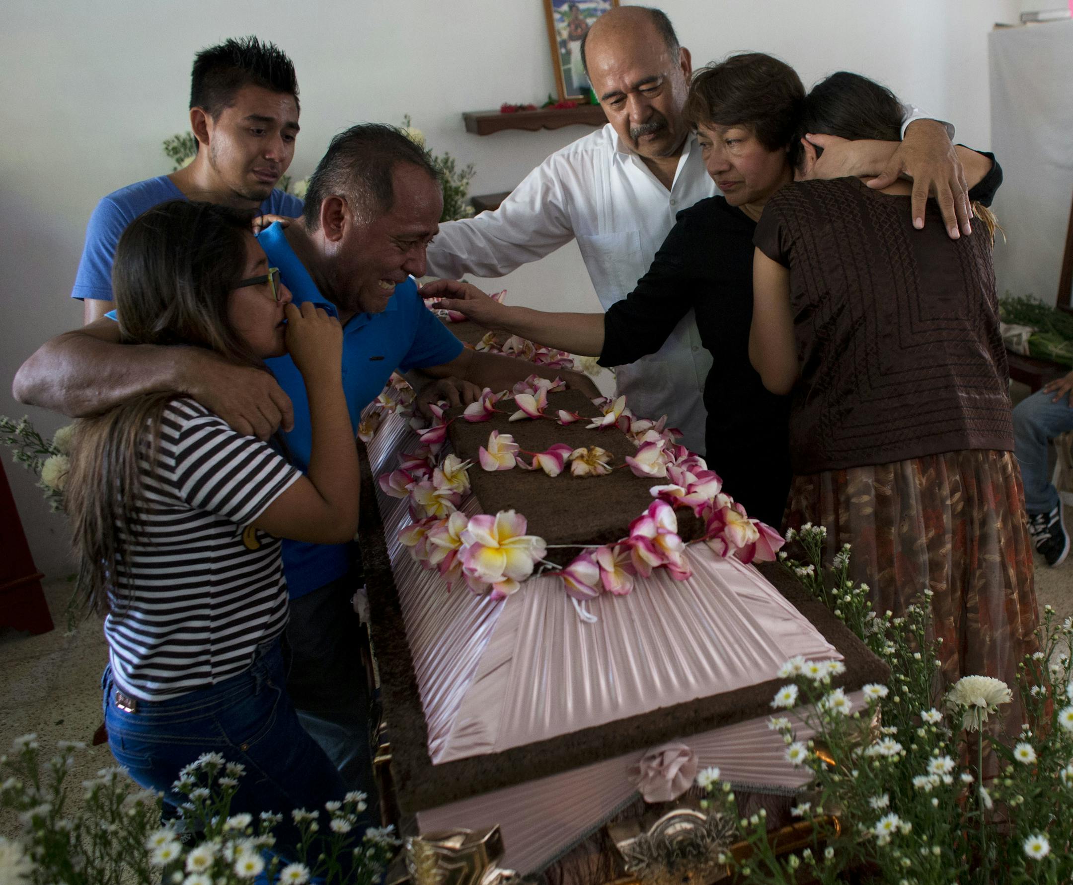 Family members grieve over the coffin containing the remains of 64-year-old Reynalda Matus during a wake in Juchitan, Oaxaca state, Mexico, Saturday, Sept. 9, 2017. Matus was killed when the pharmacy where she worked nights collapsed during Thursday's massive earthquake.(AP Photo/Rebecca Blackwell)