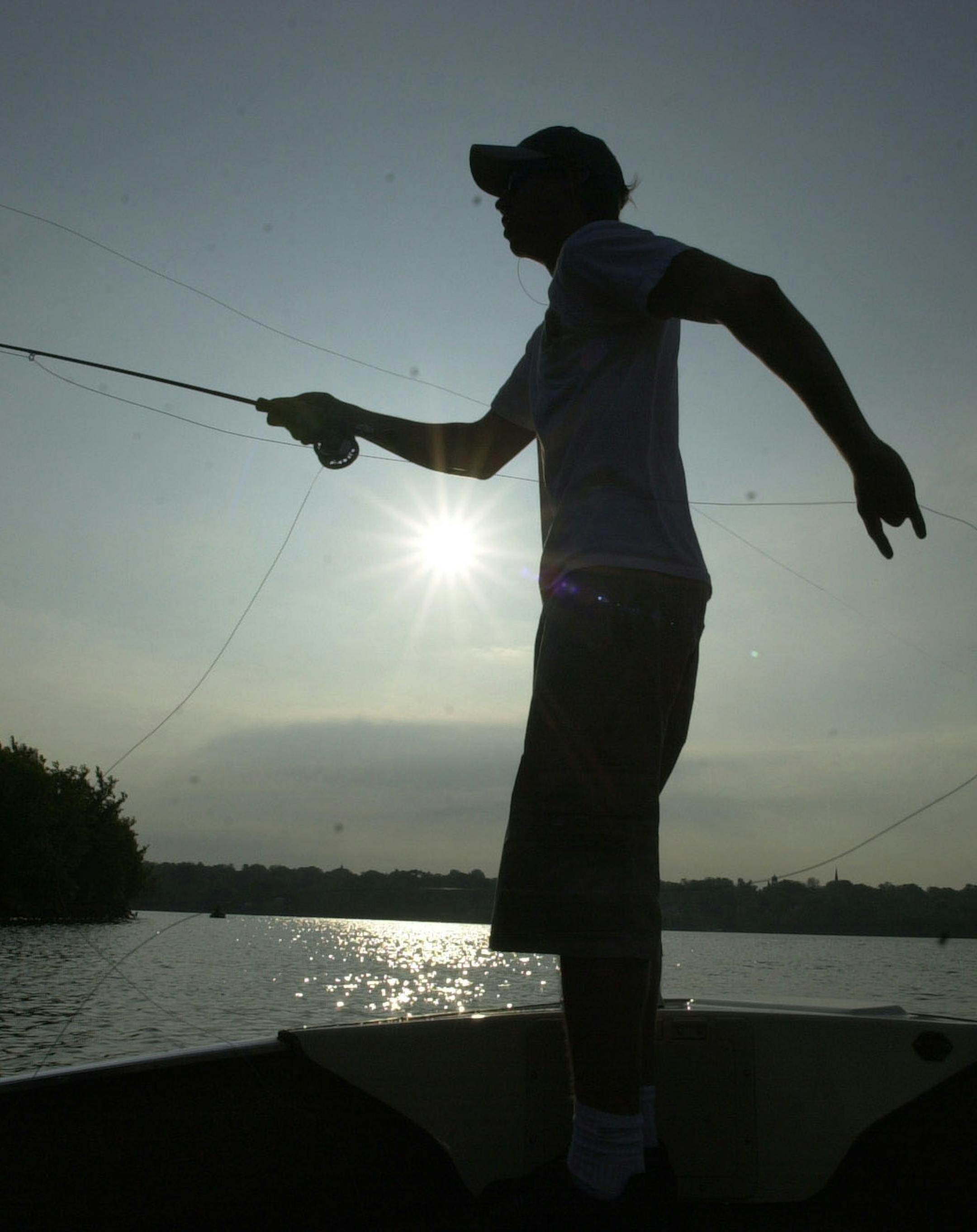 Silhouetted by the rising sun, Bobby McGraw of St. Paul casts a fly toward the St. Croix River shoreline in search of smallmouth bass. ORG XMIT: MIN2014053014305057