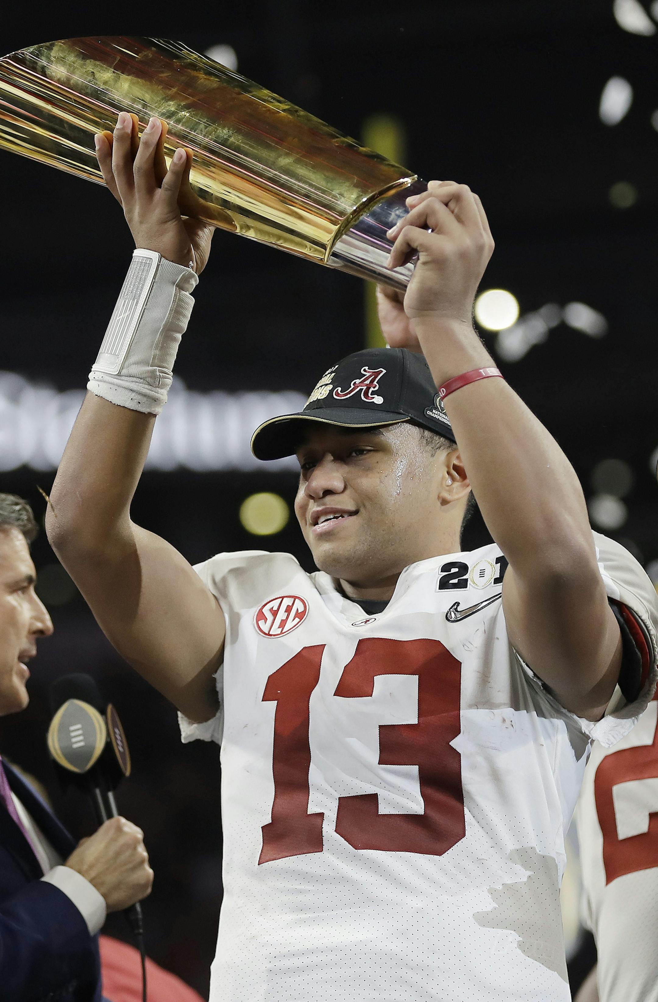 Alabama's Tua Tagovailoa holds up the championship trophy after overtime of the NCAA college football playoff championship game against Georgia, Monday, Jan. 8, 2018, in Atlanta. Alabama won 26-23. (AP Photo/David J. Phillip)