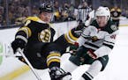 Boston Bruins center Ryan Donato, left, goes airborne after being hit by Minnesota Wild defenseman Nick Seeler during the second period of an NHL hock