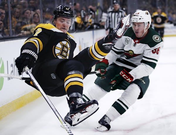 Boston Bruins center Ryan Donato, left, goes airborne after being hit by Minnesota Wild defenseman Nick Seeler during the second period of an NHL hock