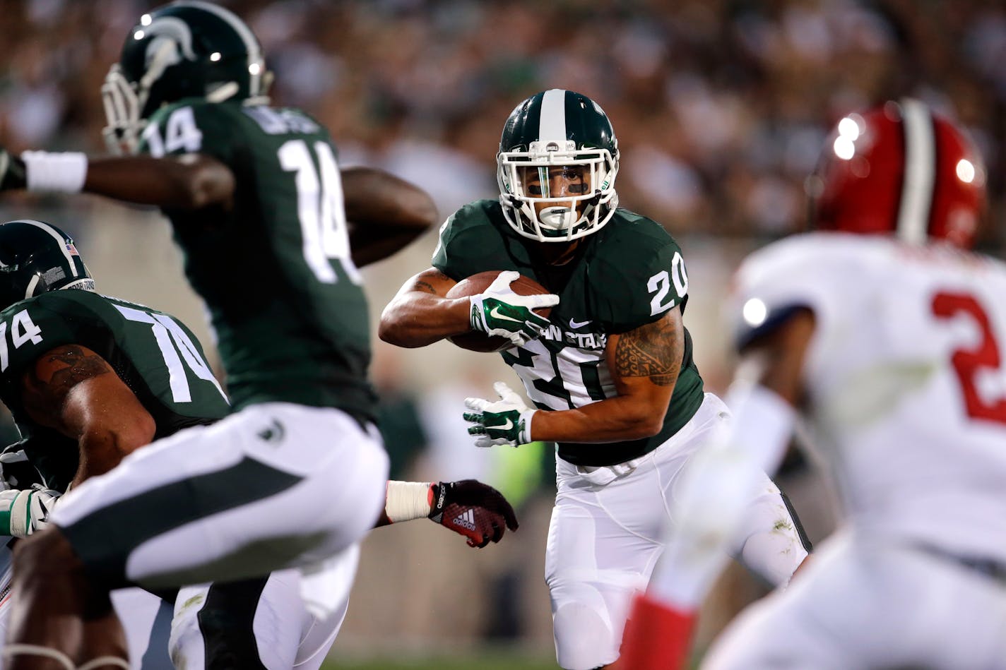 FILE - In this Aug. 29, 2014, file photo, Michigan State running back Nick Hill (20) looks for running room on a 17-yard touchdown run against the Jacksonville State.