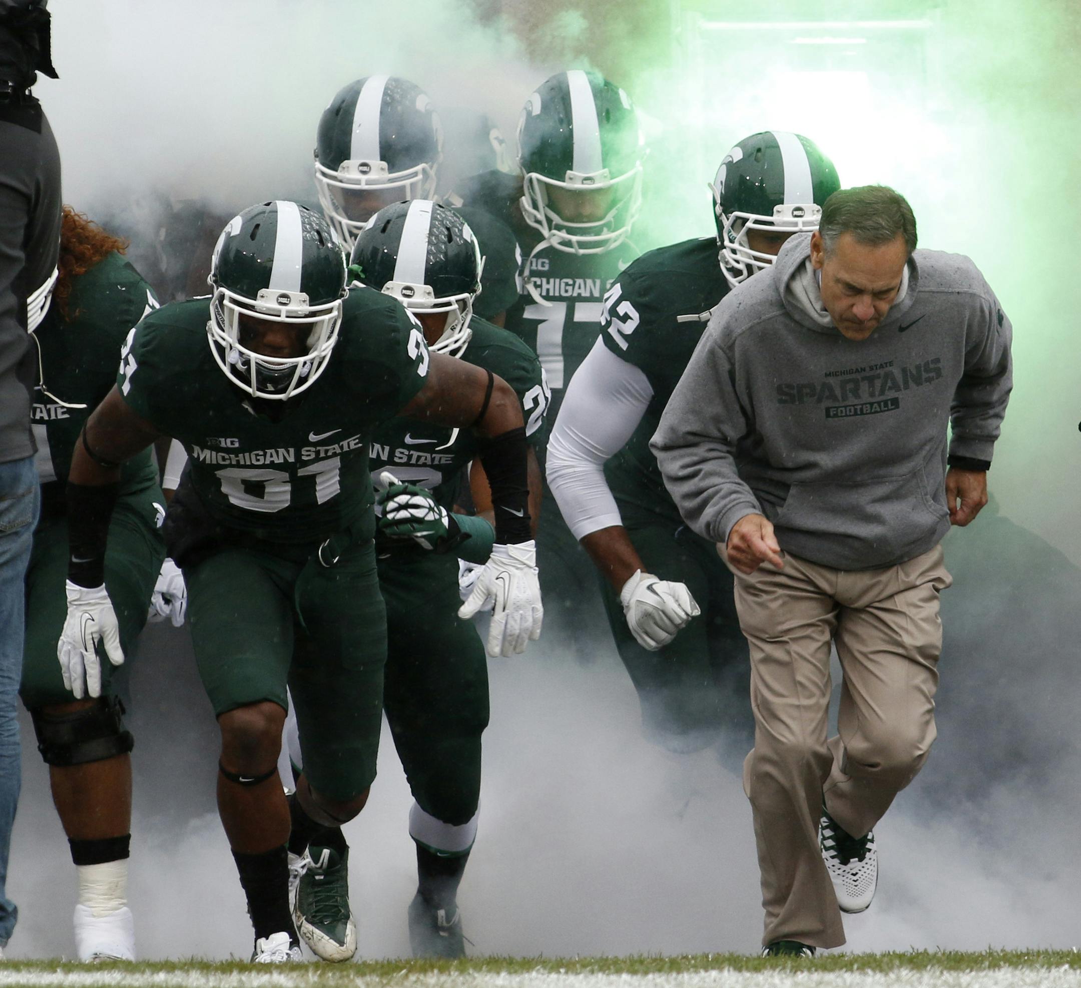 Michigan State's Darqueze Dennard, left, and coach Mark Dantonio, right, run onto the field before a game against Michigan.
