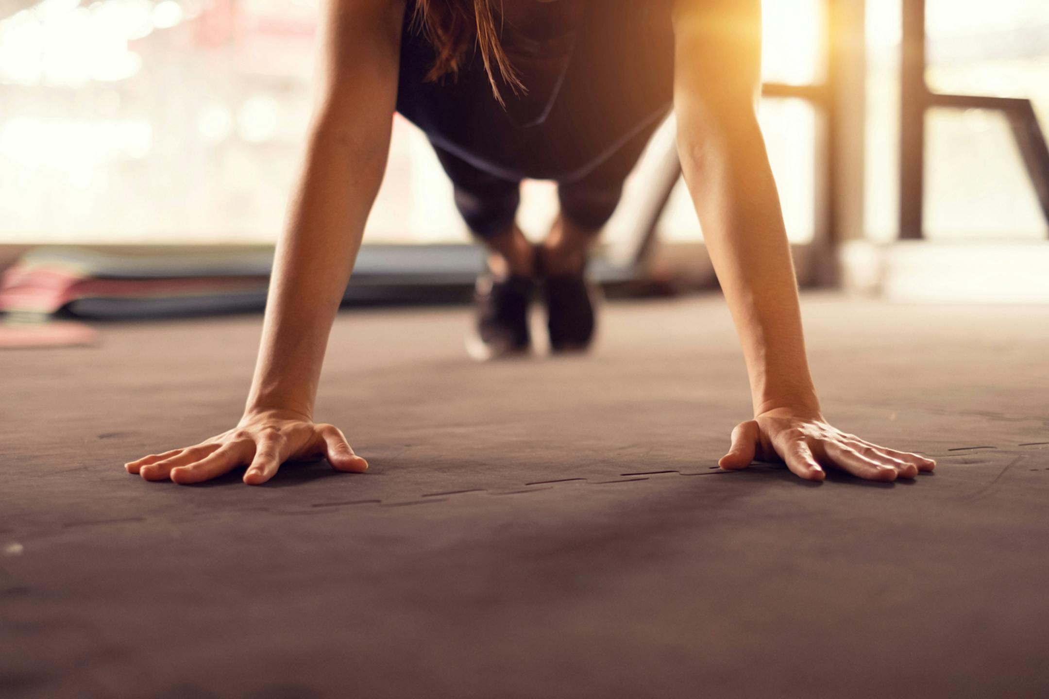 istock Woman doing push ups exercise in a gym in morning, sunlight effect.