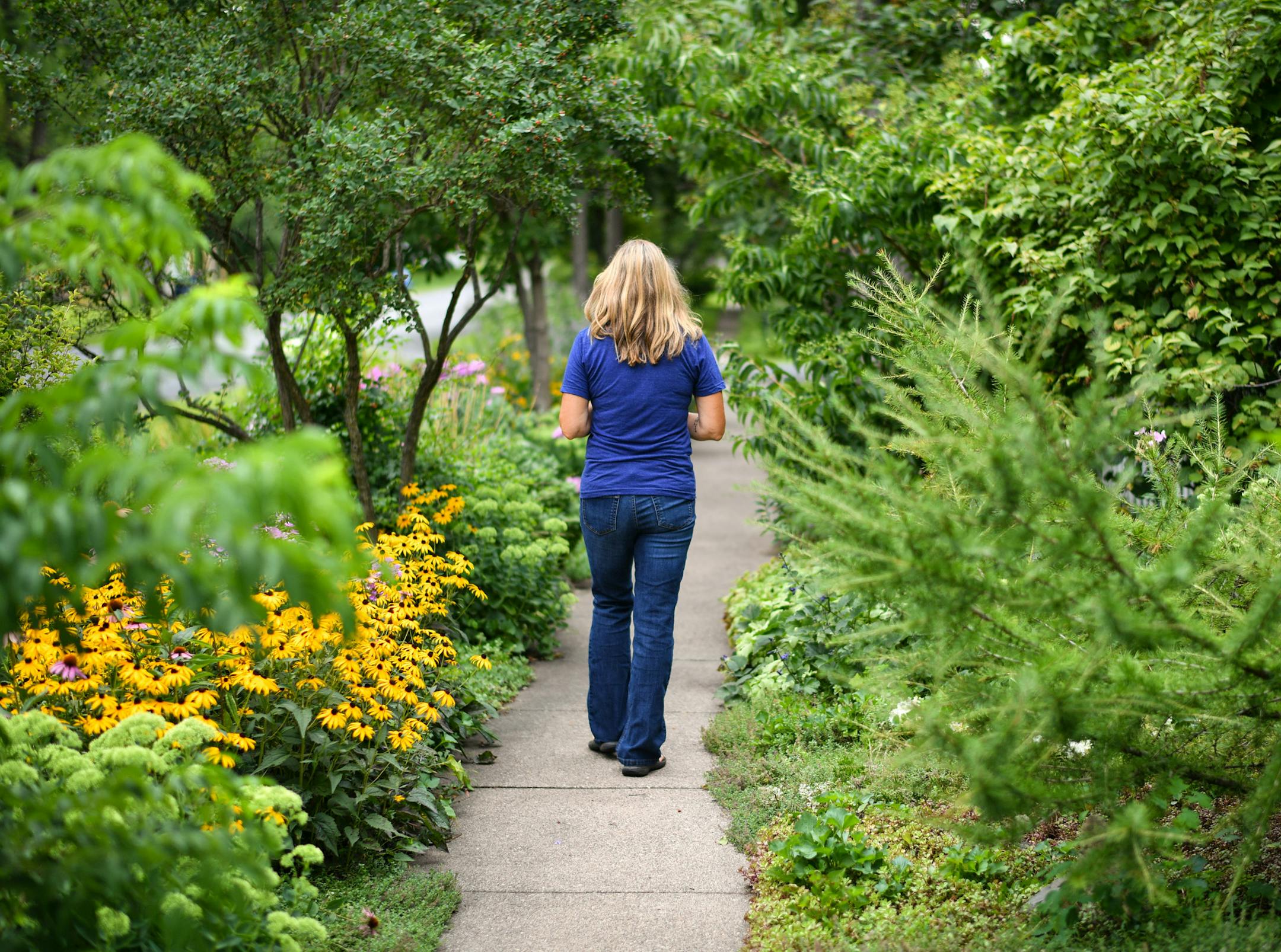 Tammy Jorgenson tends a boisterous boulevard garden (top) on the large corner lot of her Bayport home. Her front entry garden won a local award.