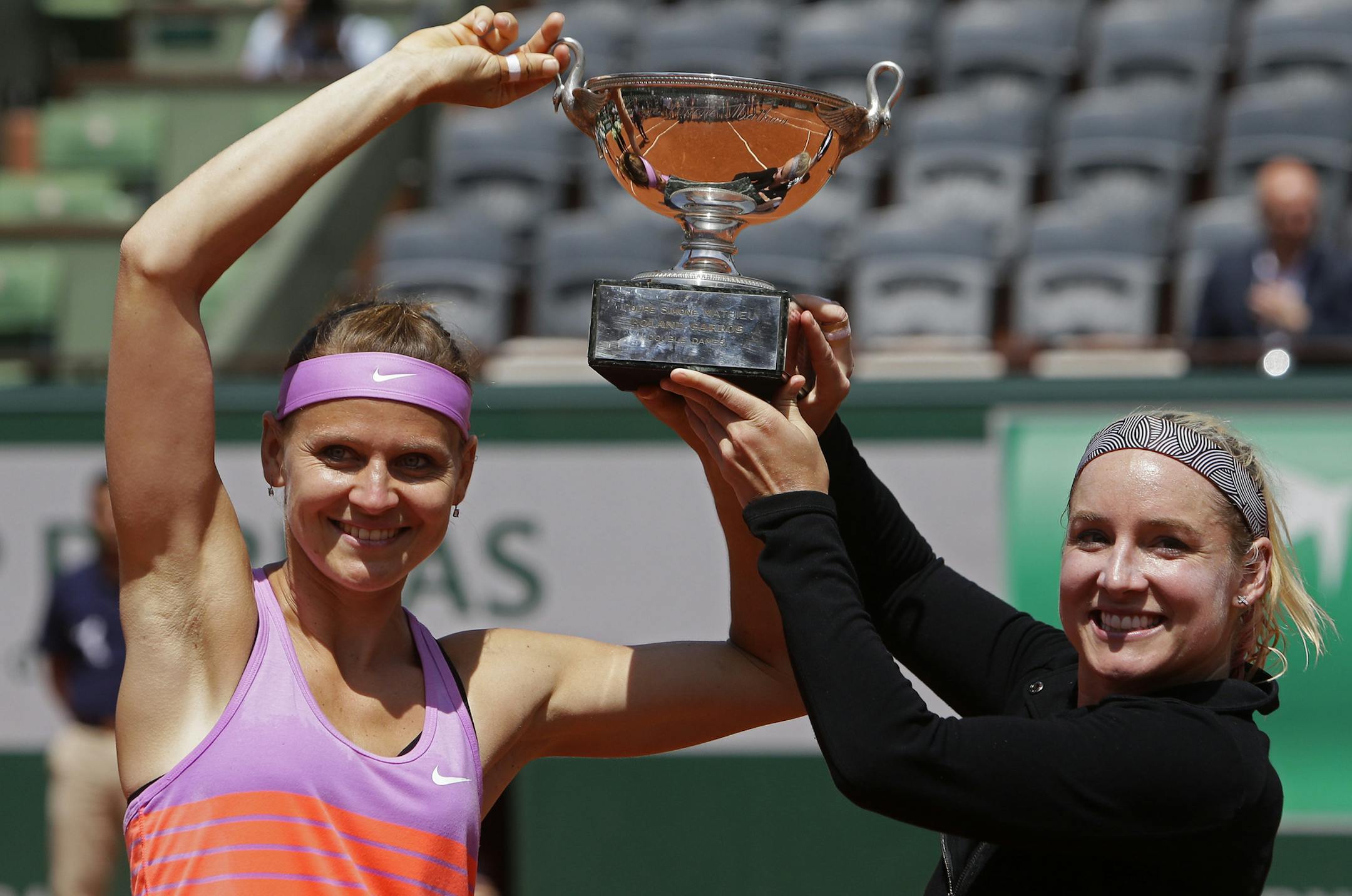 Bethanie Mattek-Sands of the U.S., right, and Lucie Safarova of the Czech Republic, left, hold the trophy after winning the women's doubles final of the French Open tennis tournament in three sets, 3-6, 6-4, 6-2, against Casey Dellacqua of Australia and Yaroslava Shvedova of Kazakhstan at the Roland Garros stadium, in Paris, France, Sunday, June 7, 2015. (AP Photo/Thibault Camus)