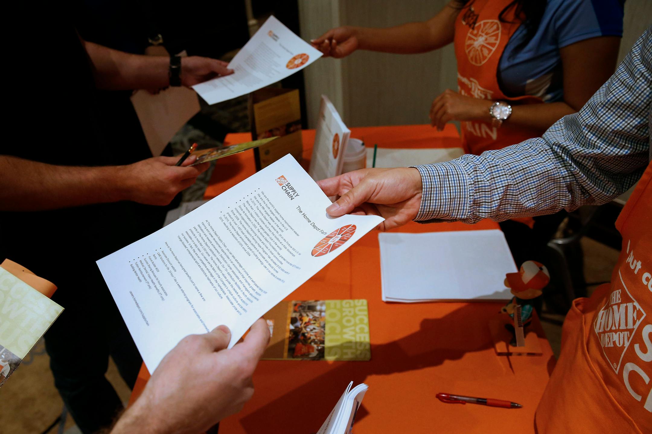 Home Depot Inc. representatives pass out flyers to job seekers at the Career Choice Inland Empire Career Fair in Ontario, California, U.S., on Wednesday, Sept. 10, 2014. The U.S. Department of Labor is scheduled to release intial jobless claims figures on Sept. 11, 2014. Photographer: Patrick T. Fallon/Bloomberg