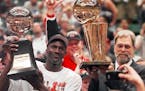 Michael Jordan holds the MVP trophy while coach Phil Jackson holds up the championship trophy after the Chicago Bulls won the 1997-98 NBA title.
