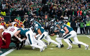 Philadelphia Eagles quarterback Jalen Hurts, center, and teammates run the tush push play during the NFL championship playoff football game against th