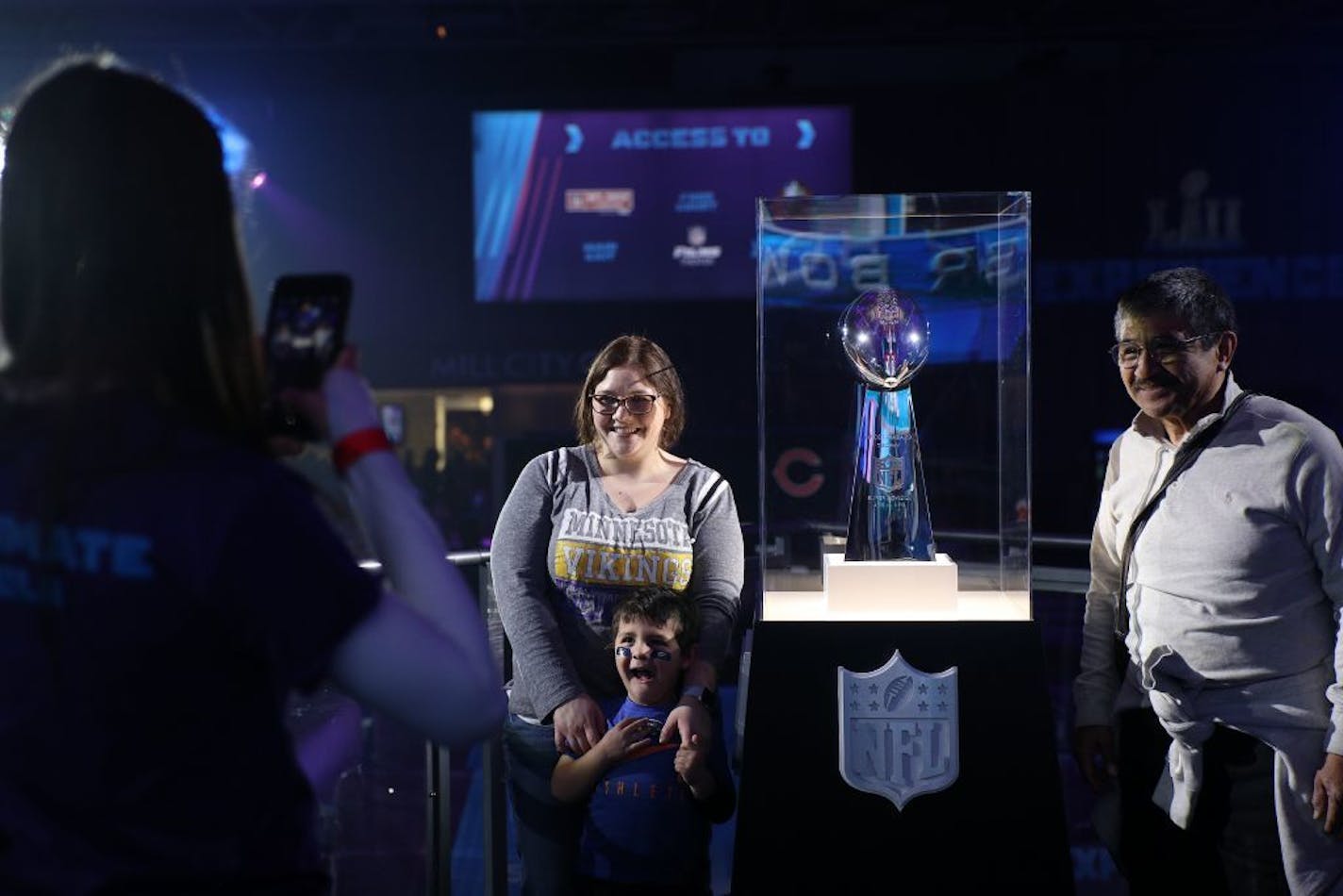 Tanya Lorenzano stood with her son Landen, 4, and father-in-law Francisco as they posed for a photo with the Vince Lombardi Trophy at the NFL's Super Bowl Experience on Saturday.