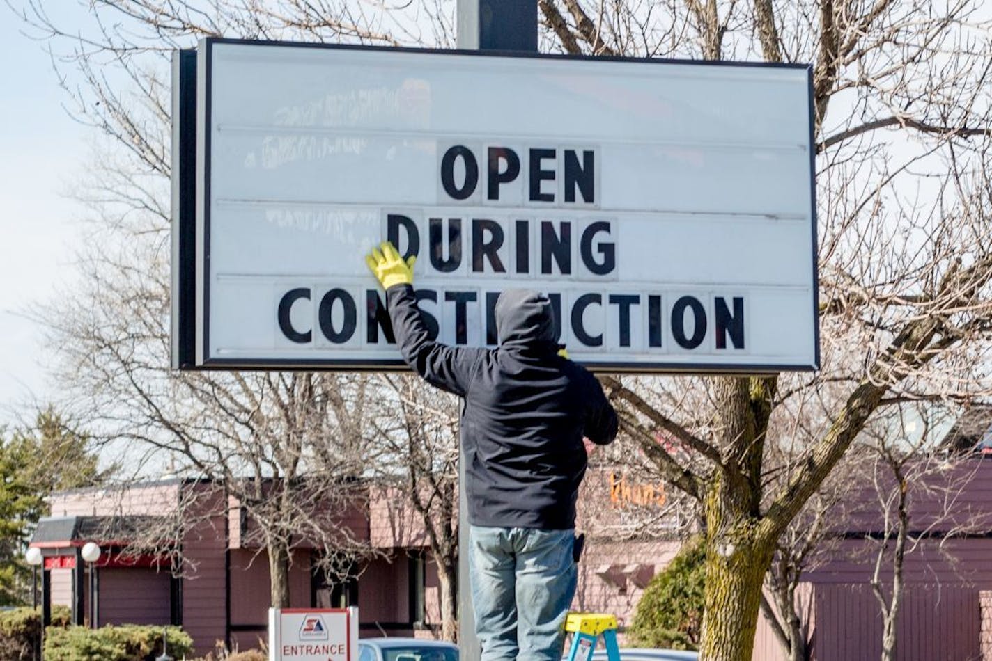 A man puts letters on the Burger King sign stating their decision to remain open.