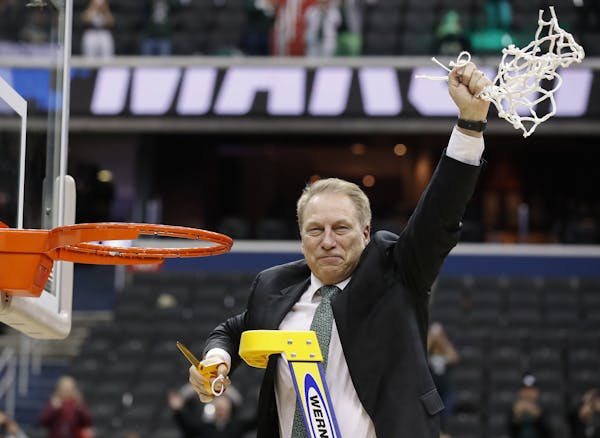 Michigan State head coach Tom Izzo holds up the net after defeating Duke in an NCAA men's East Regional final college basketball game in Washington, S
