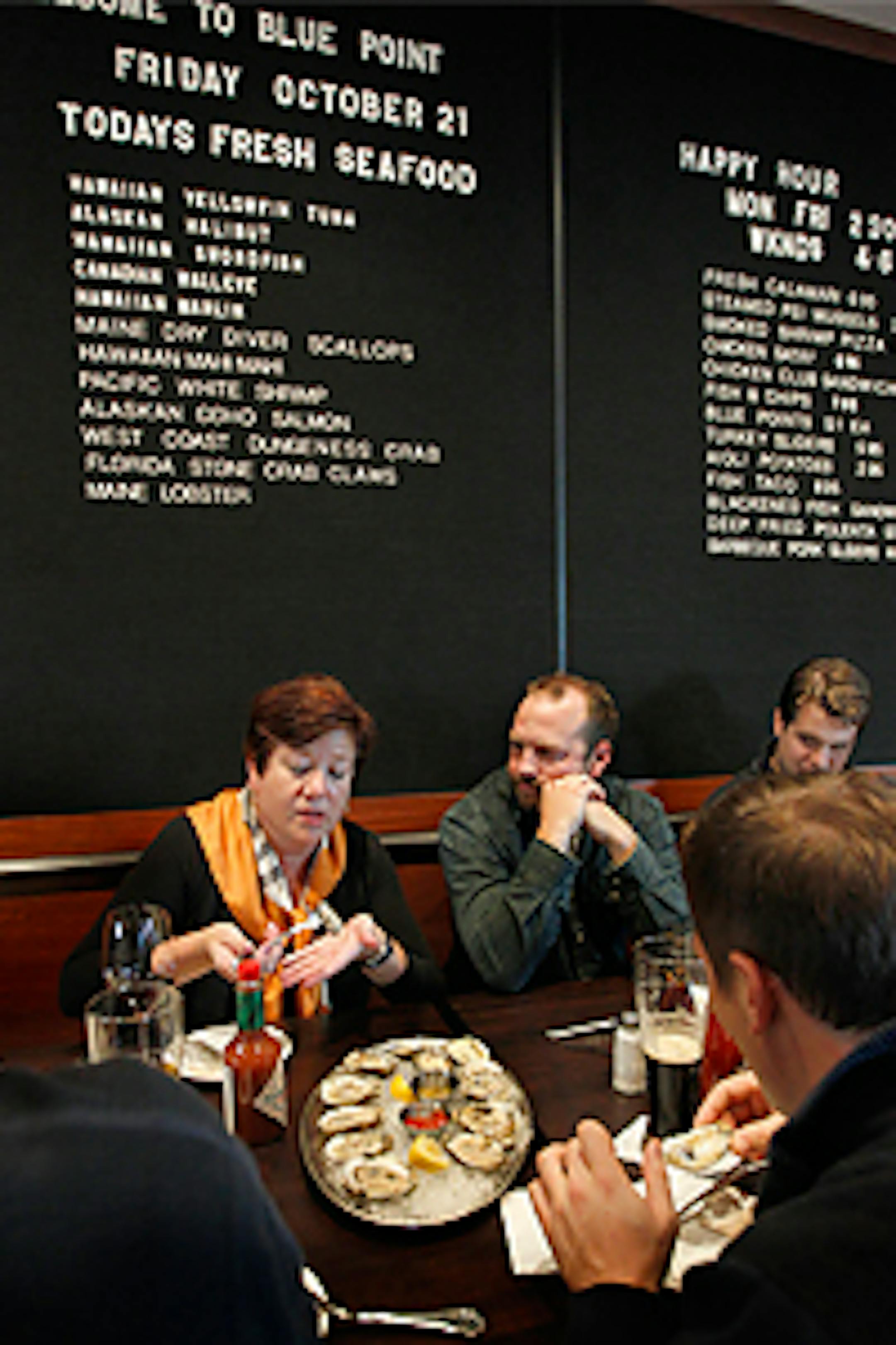 Dave Offord looks on while Liz Collins took the first bite from the platter of oysters the group shared.