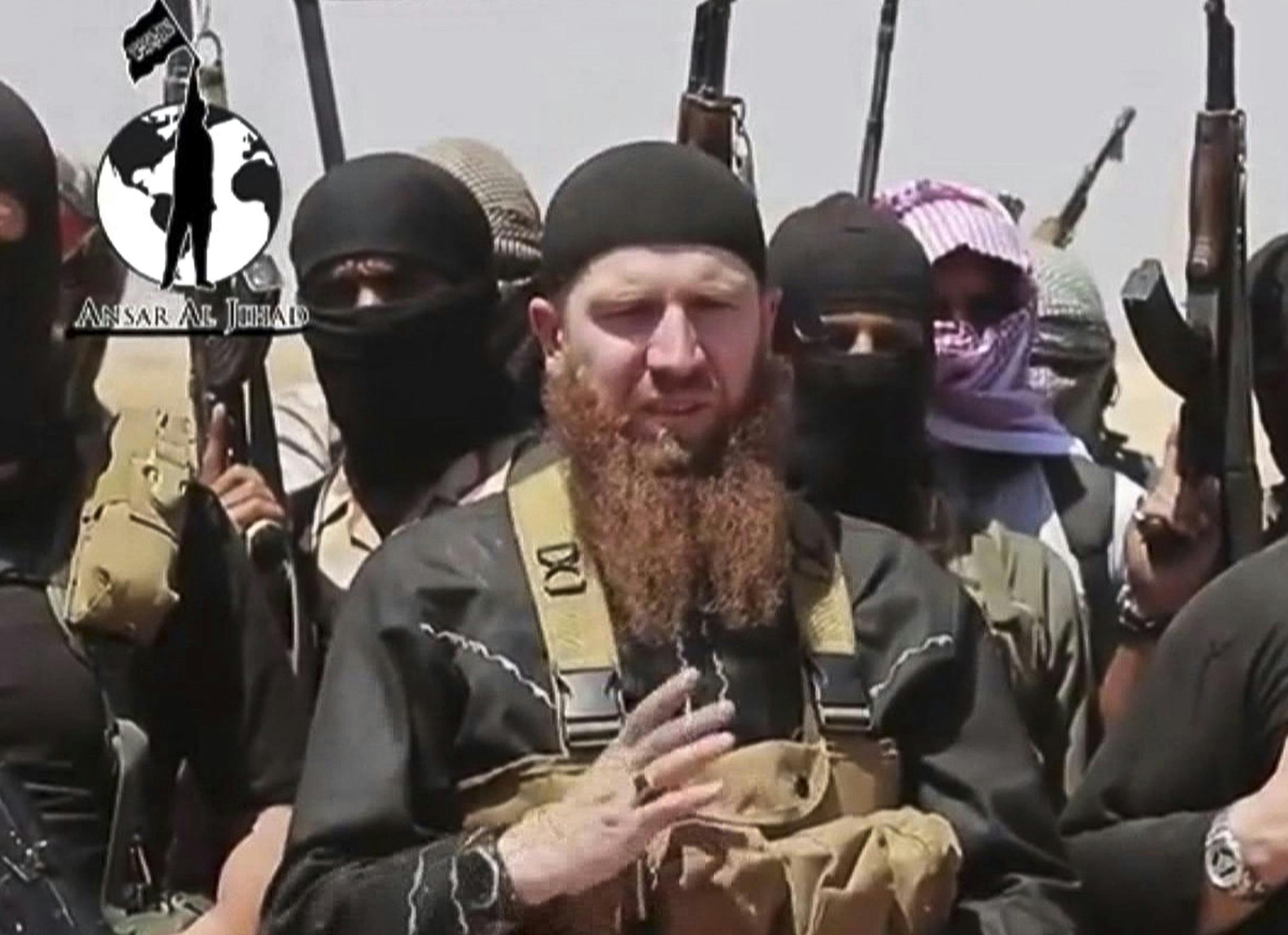 This image made from undated video posted during the weekend of June 28, 2014 on a social media account frequently used for communications by the Islamic State of Iraq and the Levant (ISIL), which has been verified and is consistent with other AP reporting, shows Omar al-Shishani standing next to the group's spokesman among a group of fighters as they declare the elimination of the border between Iraq and Syria. Al-Shishani, one of hundreds of Chechens who have been among the toughest jihadi fig