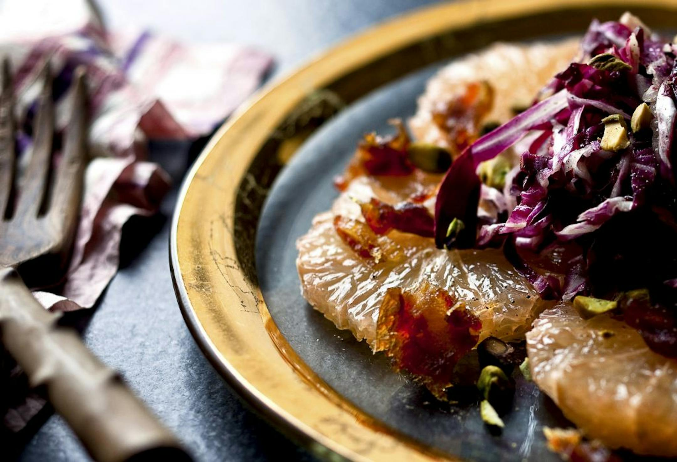 A plate of pink grapefruit and radicchio salad with dates and pistachios.