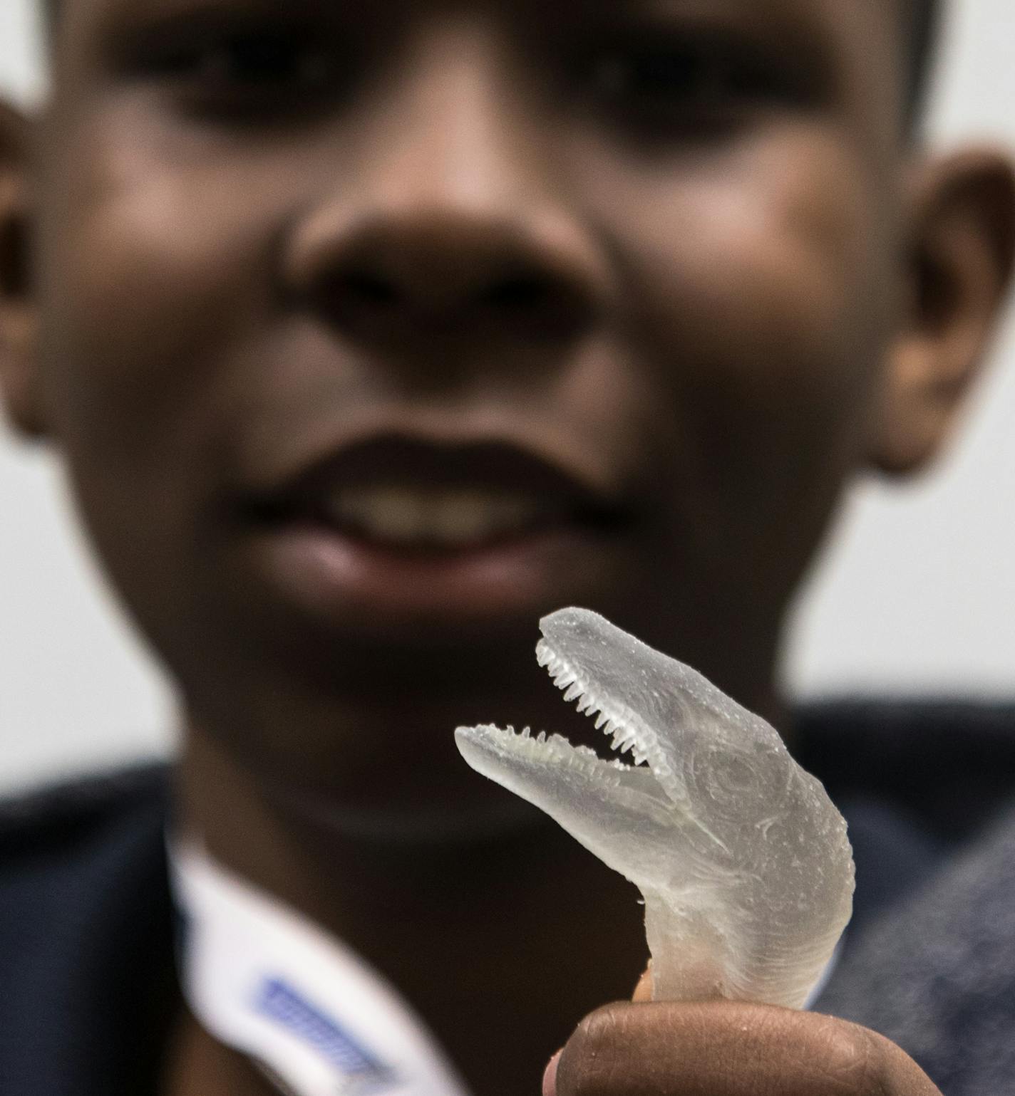 Raquawn Galloway showing off a 3-D printed velociraptor head he just cleaned at Stratasys as part of a STEM partnership with Delta Sigma Theta.