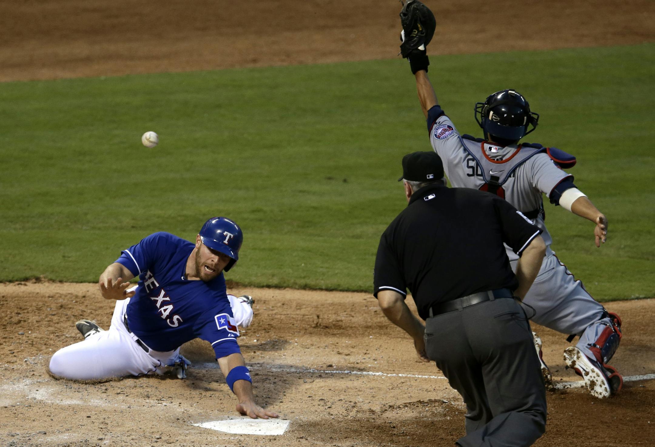 Texas Rangers' Chris Gimenez slides safely into home as umpire James Hoye, watches Minnesota Twins catcher Kurt Suzuki miss the throw in the fifth inning of a baseball game, Friday, June 27, 2014, in Arlington, Texas. Gimenez scored on a double by Luis Sardinas. (AP Photo/Tony Gutierrez)