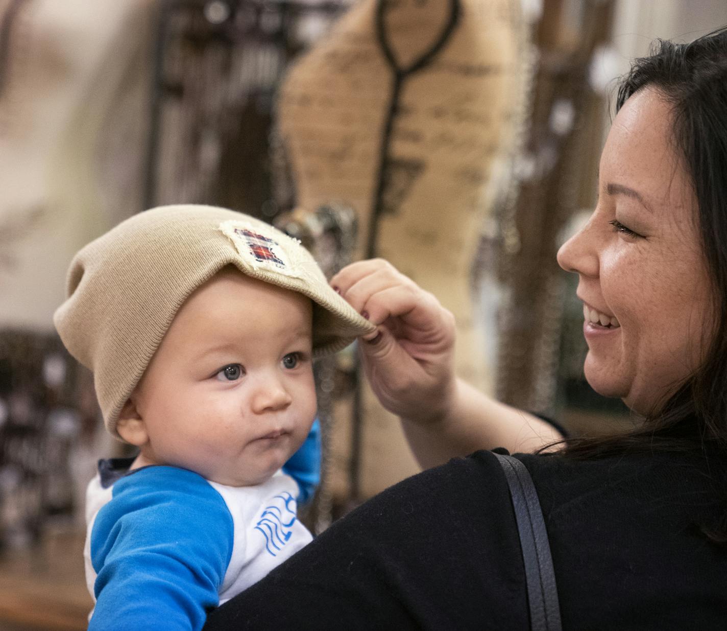 Melissa Nelson of Farmington tries a hat on her eight-month-old son Finn while shopping at Holly House Boutique. ] LEILA NAVIDI &#x2022; leila.navidi@startribune.com BACKGROUND INFORMATION: Shoppers browse for gifts at Holly House Boutique in Burnsville Center on Wednesday, December 19, 2018.