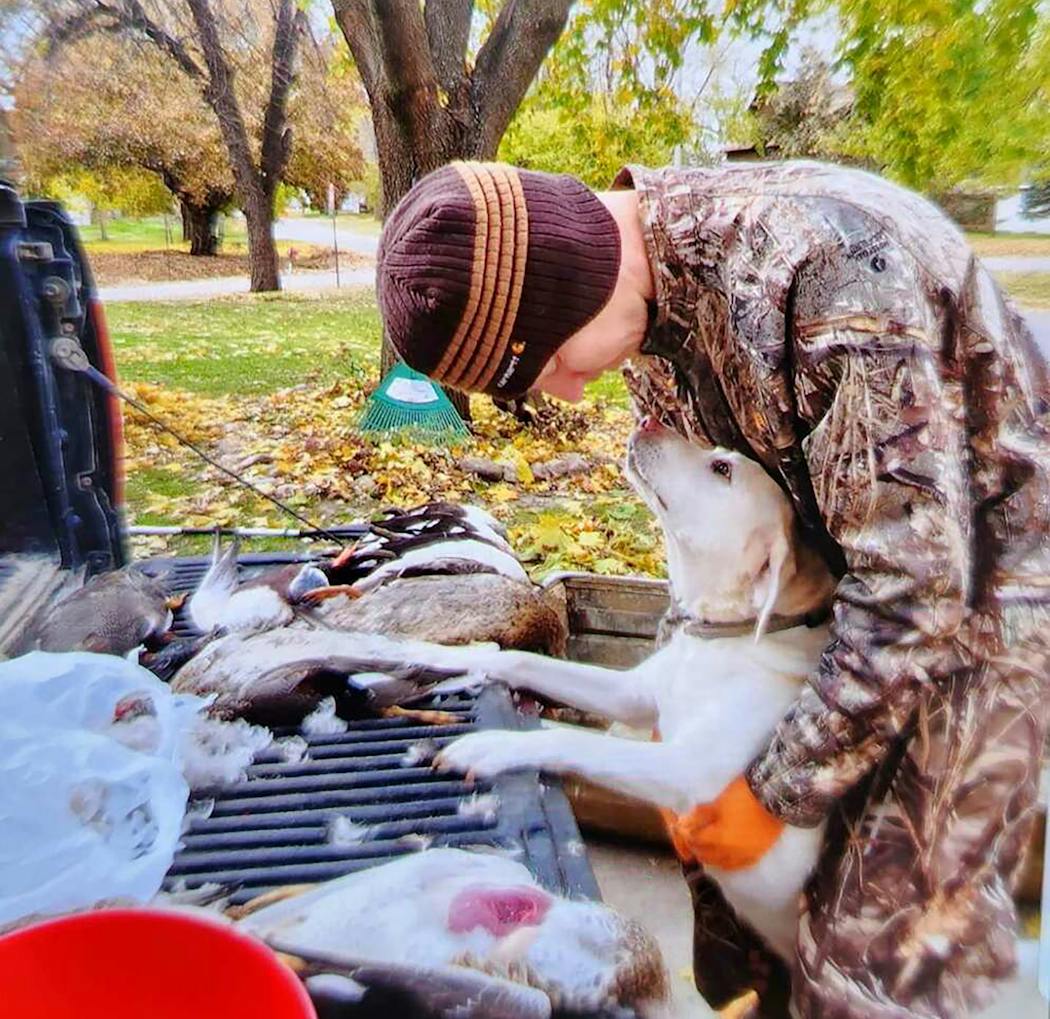 Arek Matson at age 25, cleaning ducks while hugging his uncle’s yellow Labrador.