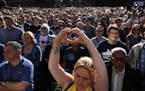 A woman makes a heart gesture as crowds gather for a vigil in Albert Square, Manchester, England, Tuesday May 23, 2017, the day after the suicide atta