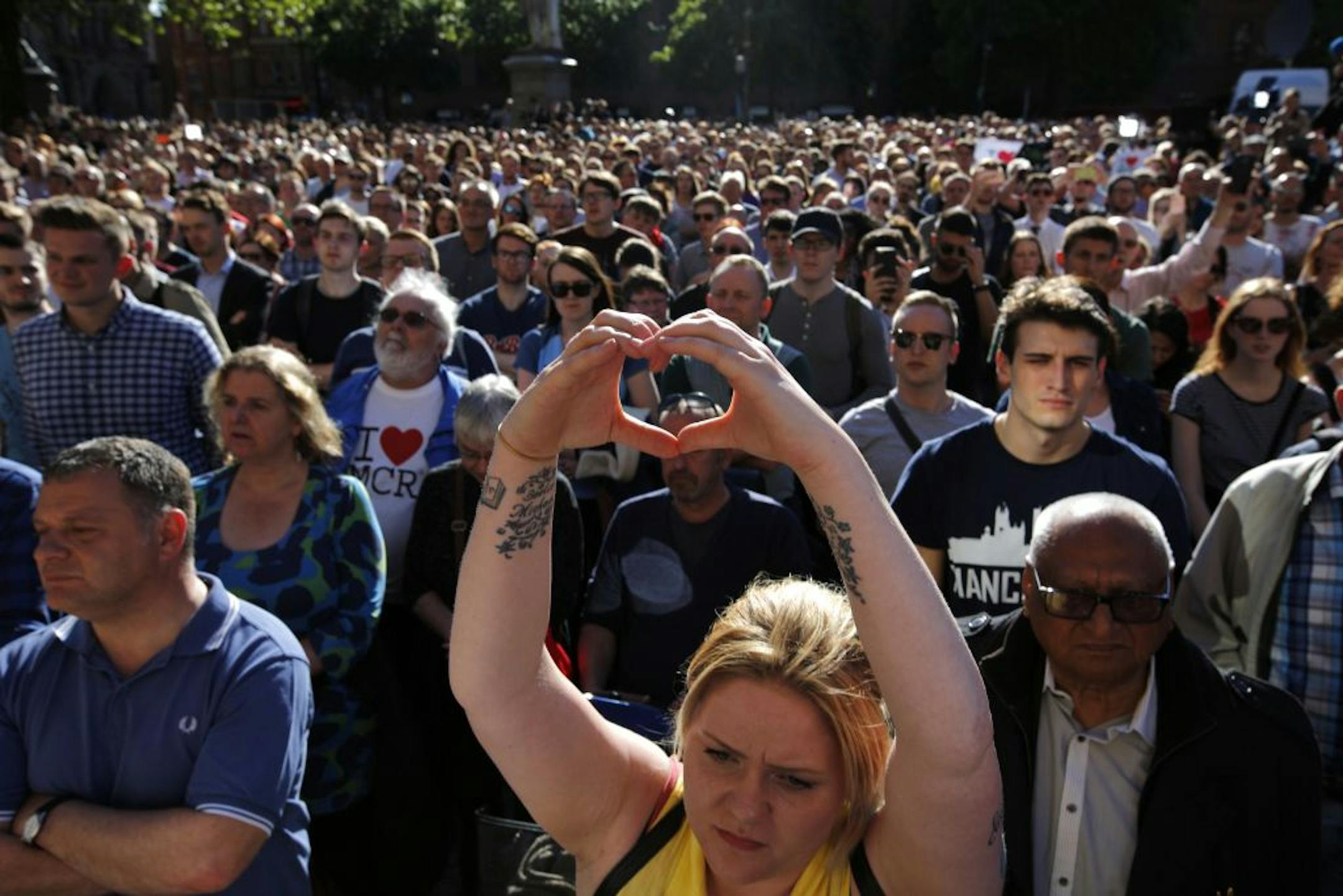 A woman makes a heart gesture as crowds gather for a vigil in Albert Square, Manchester, England, Tuesday May 23, 2017, the day after the suicide attack at an Ariana Grande concert that left 22 people dead as it ended on Monday night.