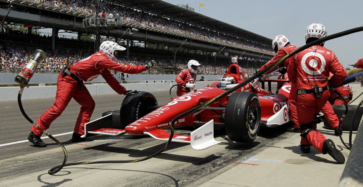 Crew members for Scott Dixon, of New Zealand, service his car during a pit stop during IndyCar's Indianapolis 500 auto race at Indianapolis Motor Speedway in Indianapolis, Sunday, May 27, 2012. (AP Photo/Darron Cummings)