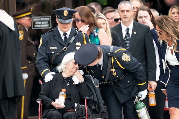 Gloria Gomm, mother of Officer Joseph Gomm, waited as her son's casket was lifted into the hearse which would take him to the cemetery. He was killed 