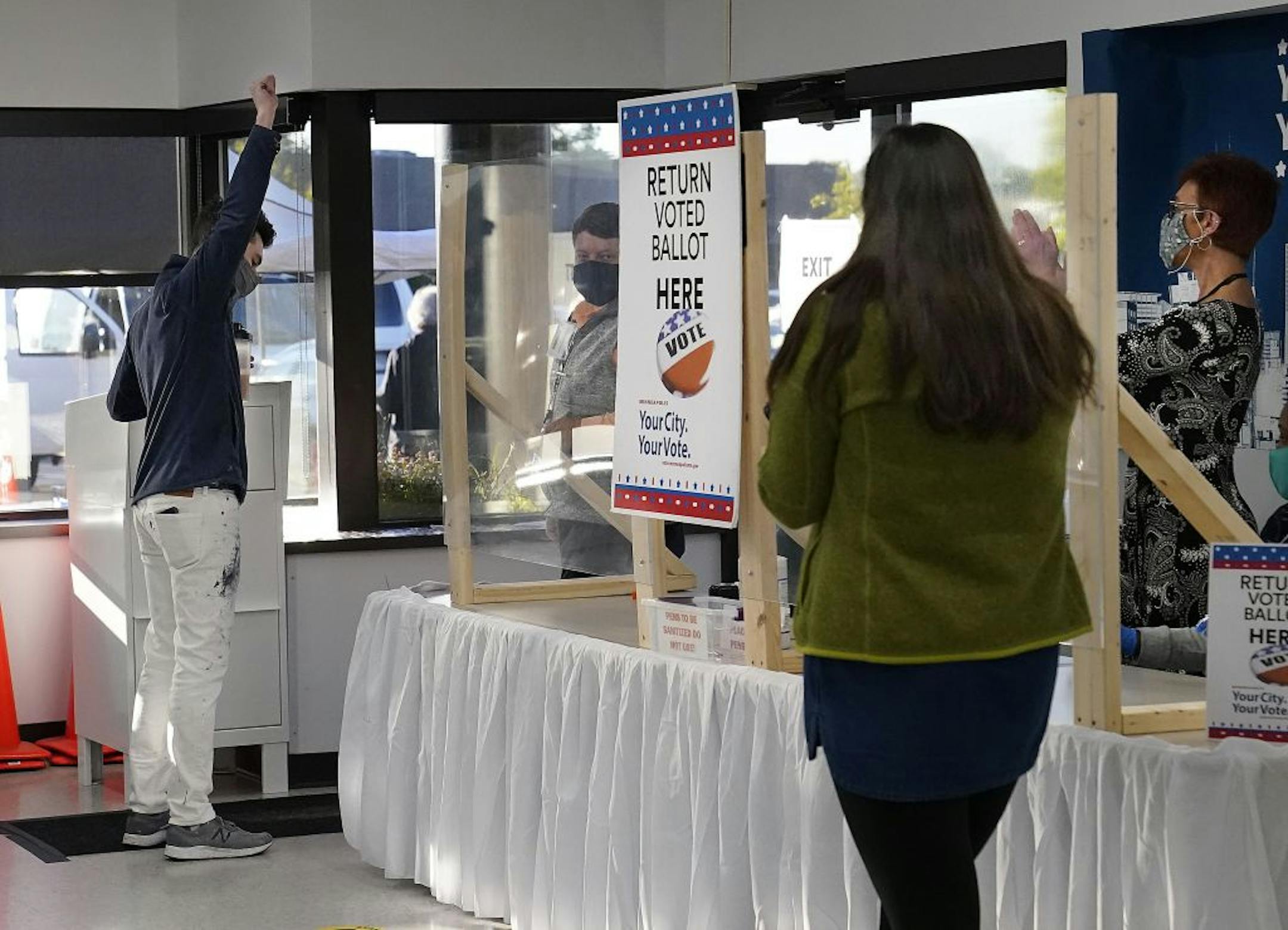 Jason Miller of Minneapolis, who was the first in line for early voting, raised his fist after being the first person to vote and place his ballot in the ballot box at Minneapolis Elections and Voter Services Friday in Minneapolis.