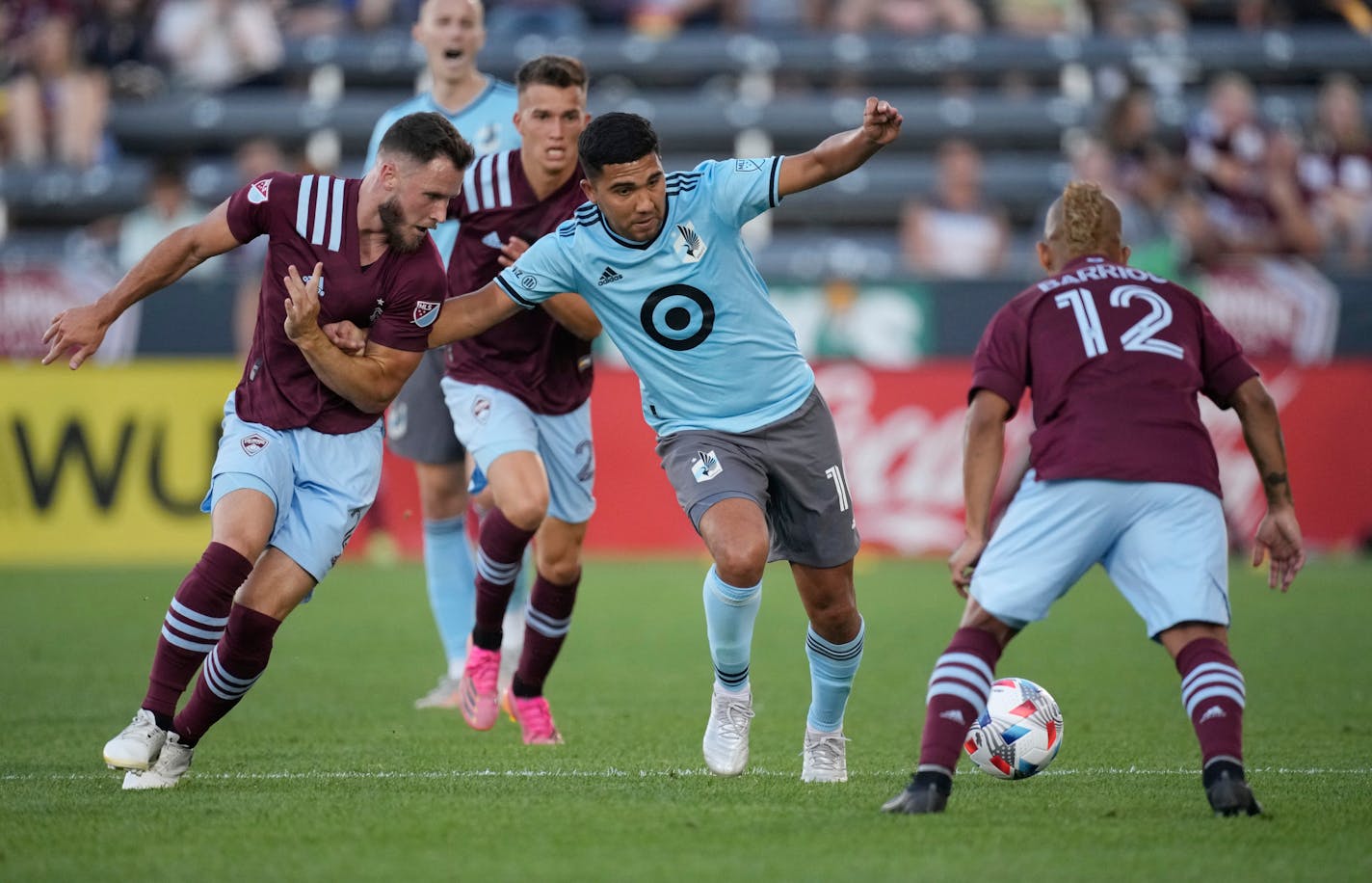 Minnesota United midfielder Emanuel Reynoso, center, vies for control of the ball with Colorado Rapids defender Keegan Rosenberry, left, and forward Michael Barrios during the first half