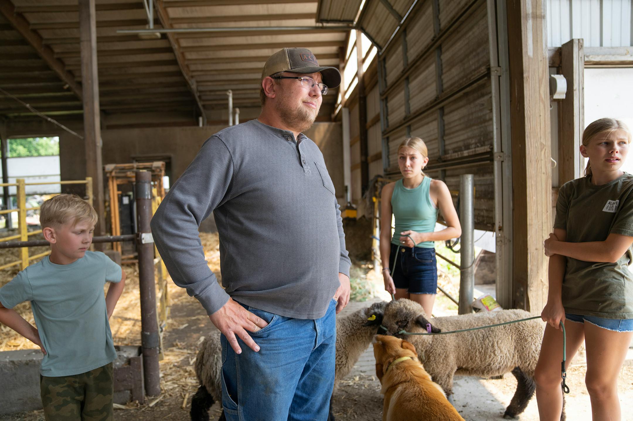 Carey Tweten stands in the barn with three of his children, Llewyn, 8, Emerson, 14, and Avyn, 12, left to right, Wednesday, June 15, 2023, at Valley Acres Dairy in Lewiston, Minn.