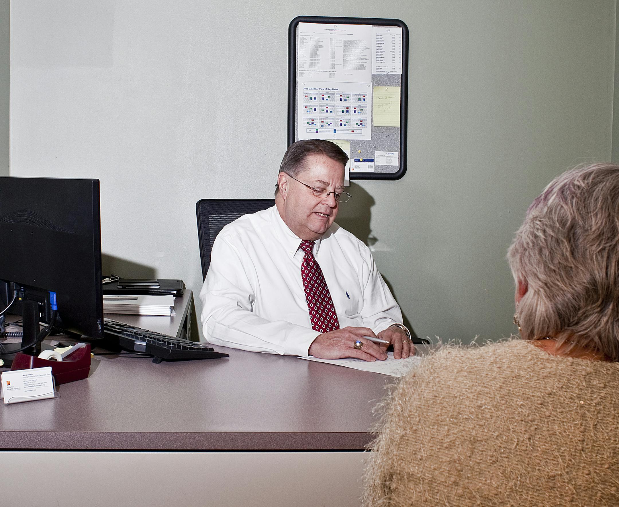 Mark Keefe, who spent his career as a human resources manager at Overlook Medical Center and retired in 2014, with a client at his office in the facility in Summit, N.J., Dec. 14, 2016. The company that owns Overlook is among the growing ranks of employers that sponsor a formal program to invite retirees back into the work force, for no more than 1,000 hours a year. Keefe now returns to work every Wednesday, counseling employees who are nearing retirement about benefit packages. (Bryan Anselm/Th