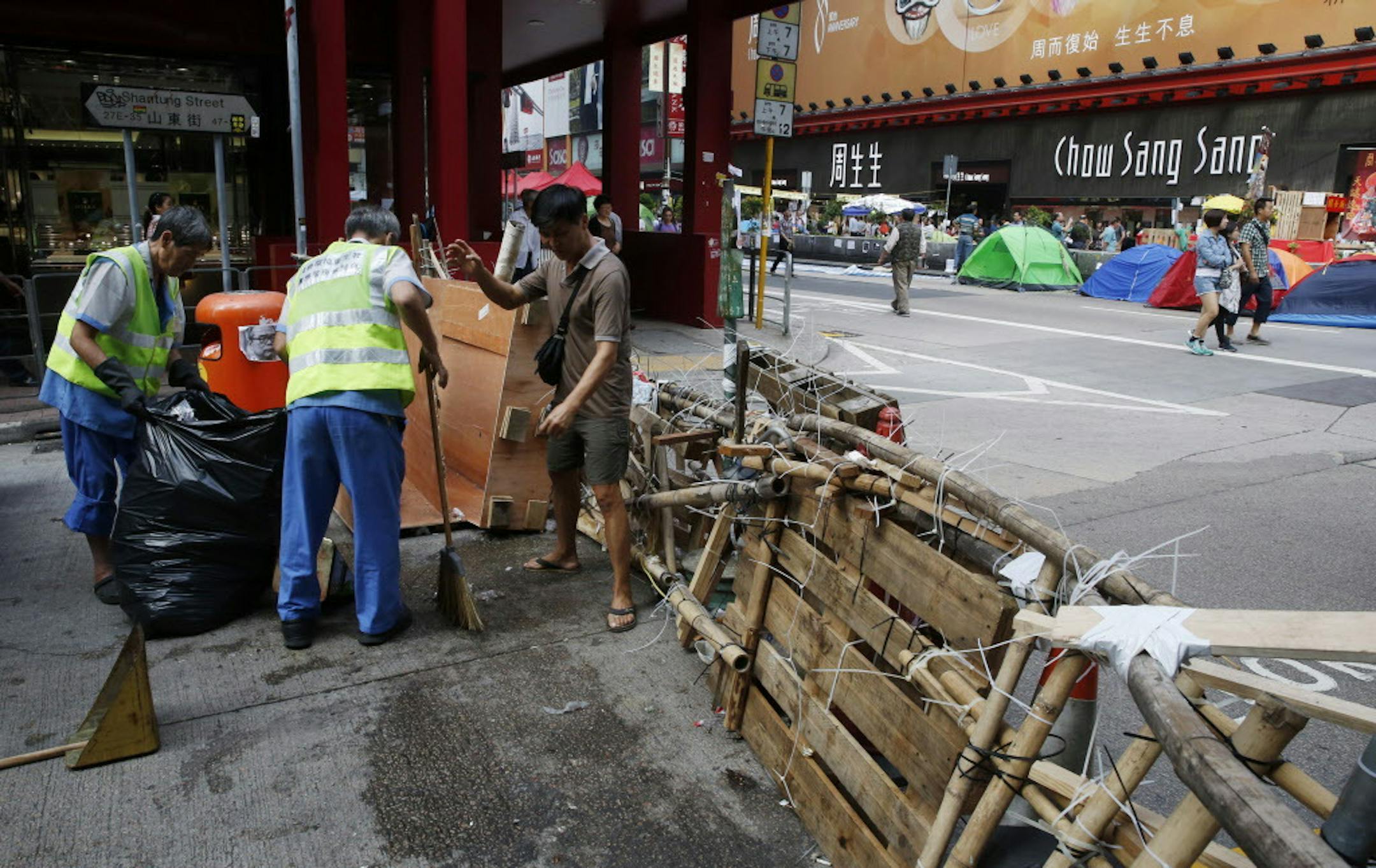 Workers clean the street near a barricade in the occupied area of the Mong Kok district of Hong Kong, Friday, Oct. 31, 2014. Hong Kong student protest leaders are considering visiting Beijing while it hosts a major Asian summit next week to press their demands for greater democratic reforms. (AP Photo/Kin Cheung)