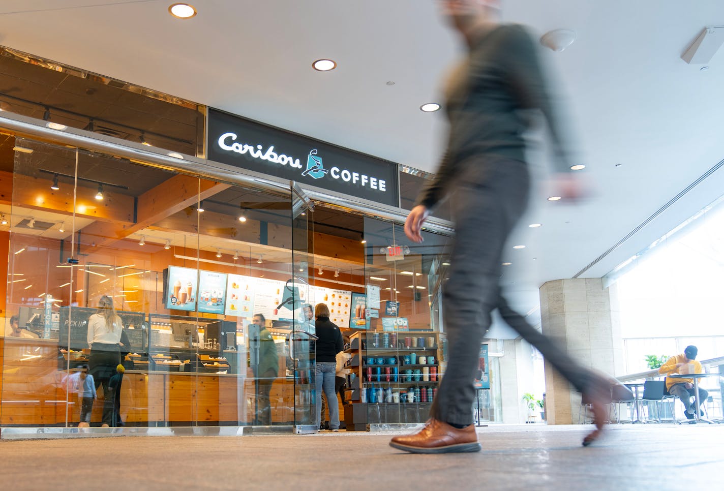 People walk past Caribou Coffee Tuesday, Feb. 28, 2023 inside the skyway in the U.S. Bank building in downtown Minneapolis. ]