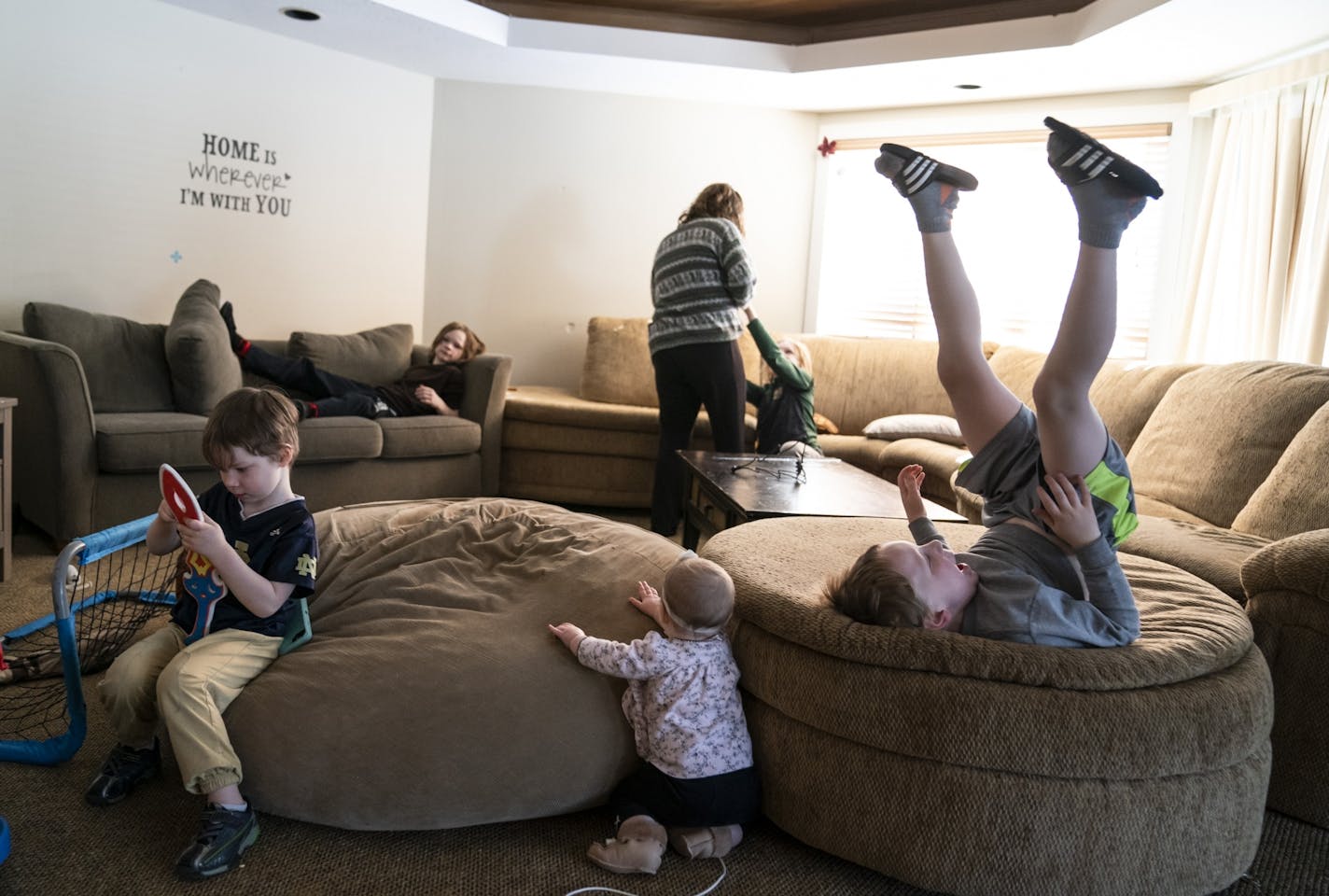 Angela Cahill, in background, grabbed a football from her oldest son Lachlan Cahill, 9, as she agreed to play football with him and her other boys during an school closure day due to the cold weather in Eagan, Minn., on Tuesday, January 29, 2019. Also pictured are her other children playing including Torin Cahill, 8, in the back couch, Beccan Cahill, 4, front left, Tressa Cahill, 7 months, center, and Callum Cahill, 6, right.