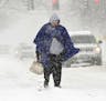 Eva Brandt walks along Genesee Street in the snow on her way to work in Auburn, N.Y., Monday, Nov. 21, 2016. A storm system is bringing wintry weather