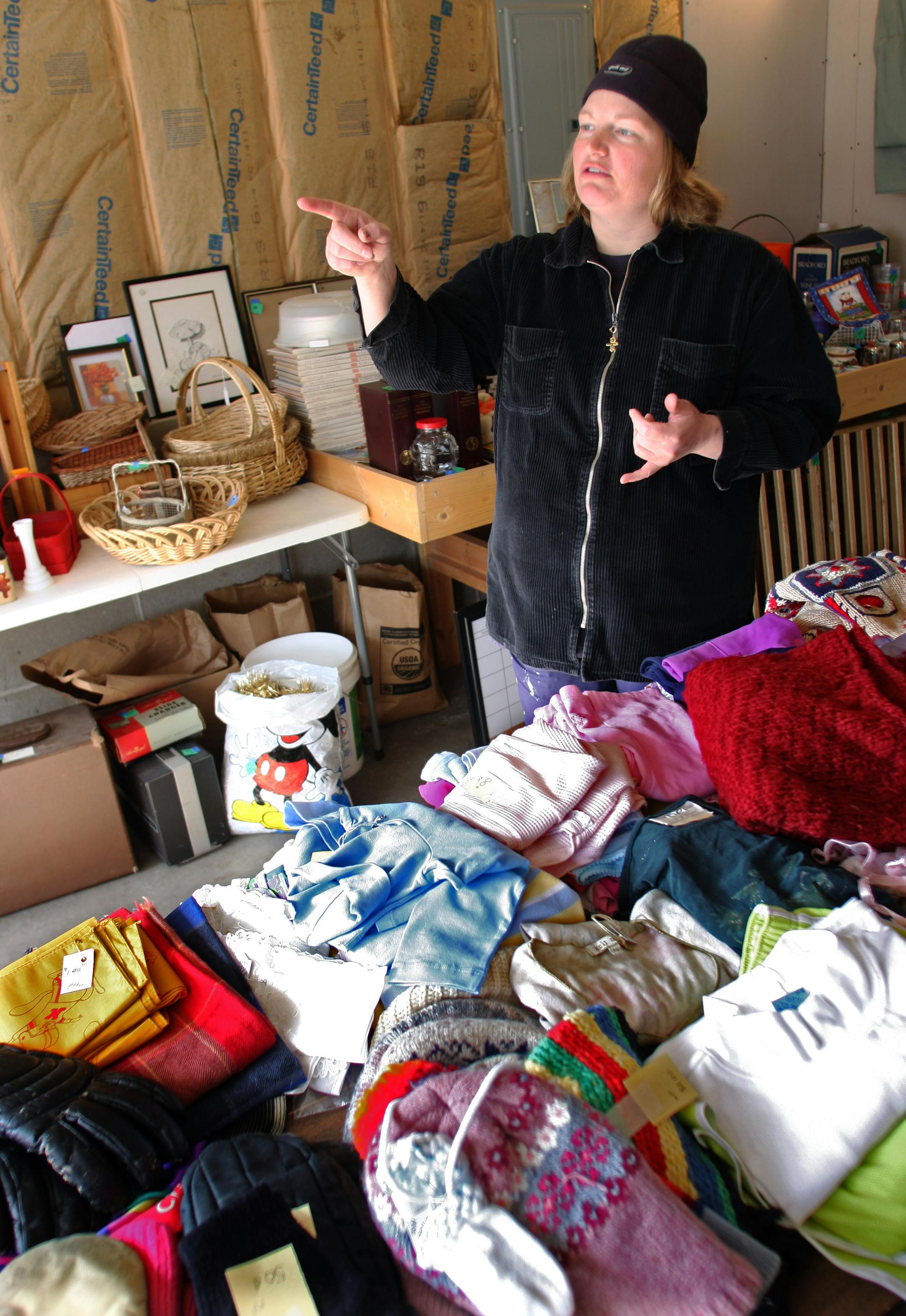 Amy Carlson pointed out items to neighbors and customers during a multi-family garage sale at her house in Minnetonka. The city may set an annual limit on the number of garage sales per household.