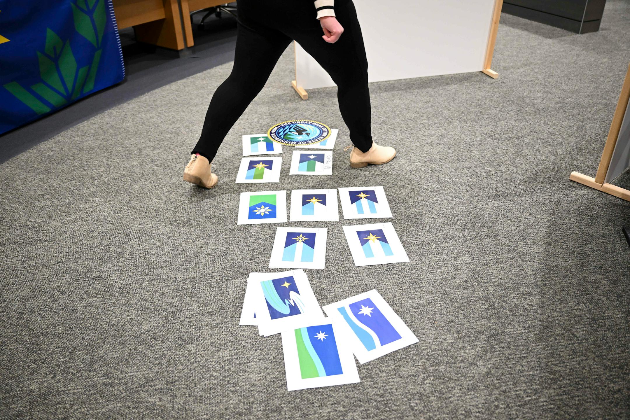 Variations of the three Minnesota state flag finalists that are no longer in consideration were placed on the floor during a meeting of the State Emblems Redesign Commission, Tuesday, Dec. 12, 2023 at the Minnesota Senate Building in St. Paul, Minn.. ] AARON LAVINSKY • aaron.lavinsky@startribune.com