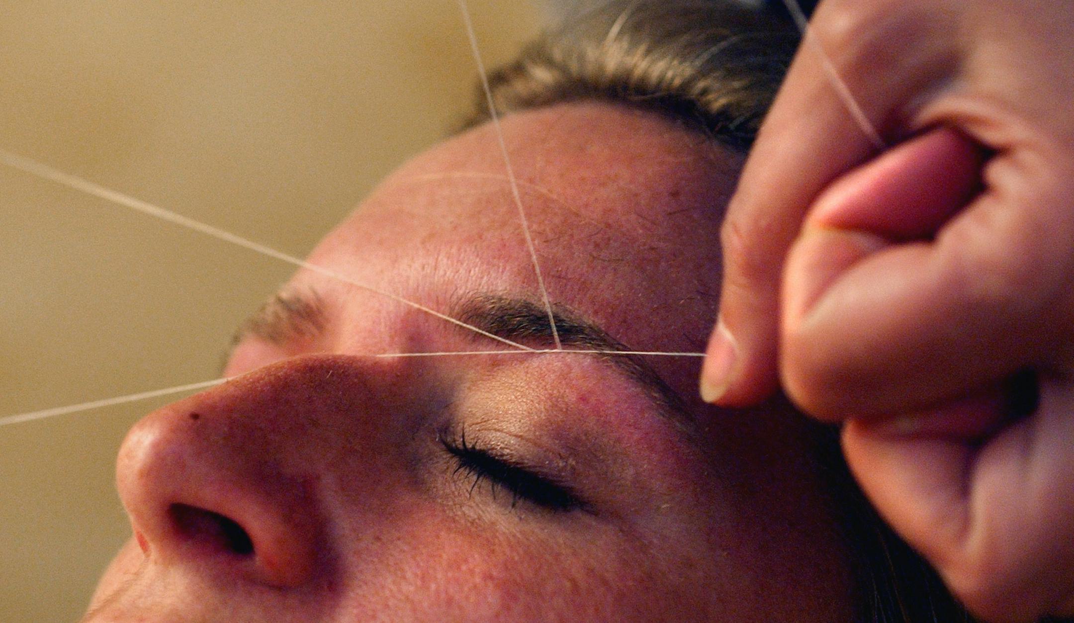 Bloomington, Mn., Thurs., May 22, 2003--Zari Bakhtiari, who practices the ancient art of threading (removing facial hair with a string), shapes eyebrows on Bridget Gaffney of Minneapolis. GENERAL INFORMATION: Zari Bakhtiari practices the ancient art of threading or removing facial hair with a string.