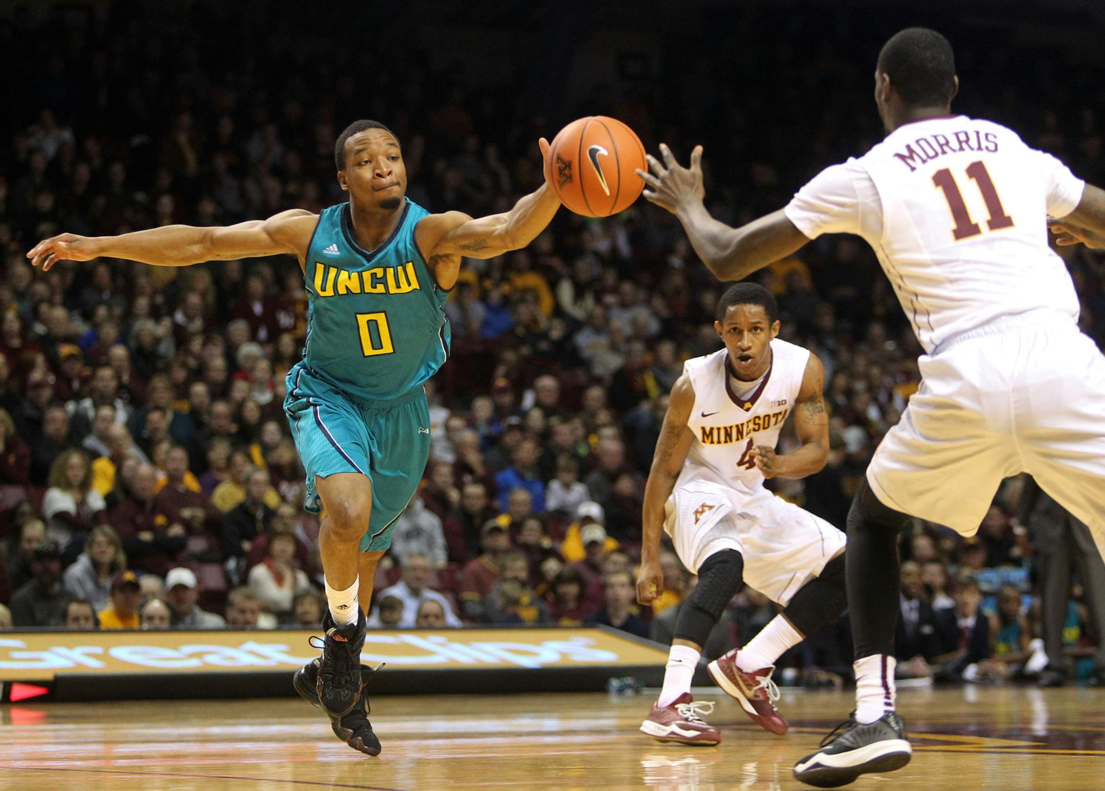 The Gophers' Carlos Morris (11) reached for a loose ball brought upcourt by UNC Wilmington's Craig Ponder (0) as Minnesota's DeAndre Mathieu (4) looked on during the first half.