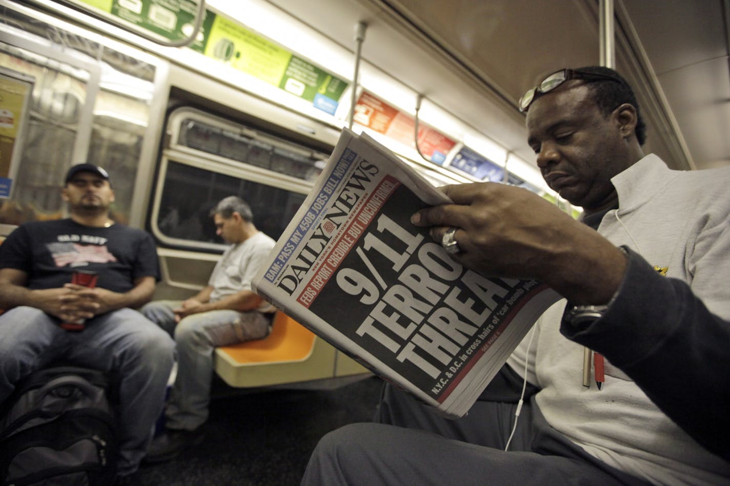 An early morning subway commuter reads a newspaper with a front page announcing news of an al-Qaida terror threat, Friday, Sept. 9, 2011 in New York.