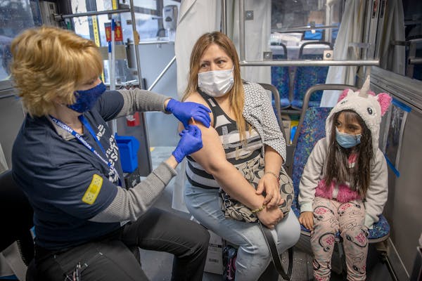 Evangelina de Santiago, alongside her daughter Alyssa Fajardo, received her COVID-19 vaccine from nurse Carol Brown at a mobile vaccine clinic in a pa
