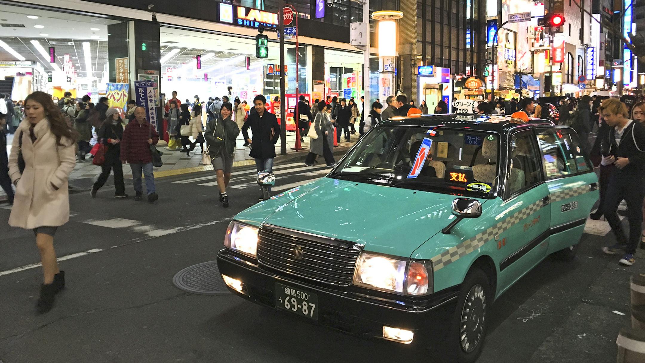 Passengers get into a waiting taxi in Japan’s Shinjuku district, the city’s Times Square-like area.